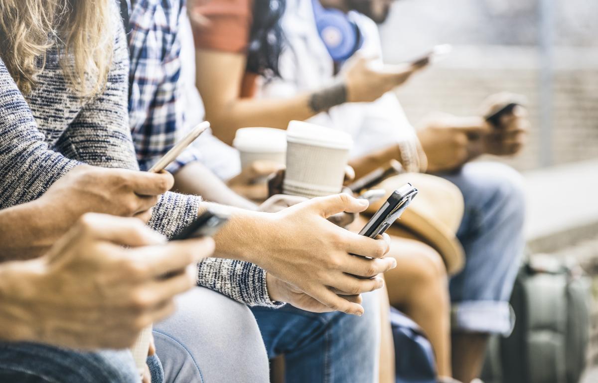 a line of young people reading smart phones