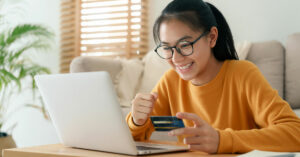 Smiling female looking at laptop with credit card.