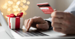Laptop, person holding a credit card; wrapped present