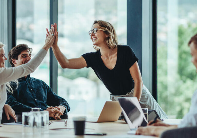 4 people in meeting; 2 women high-fiving;