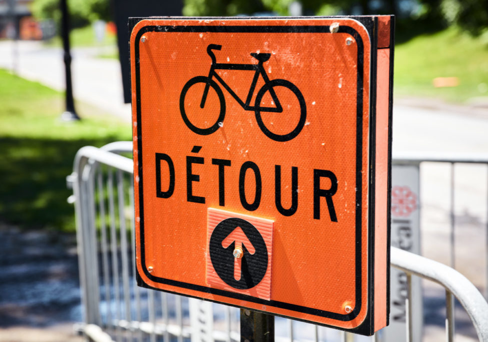 Orange road detour sign for bicycle in French. Arrow pointing straight.